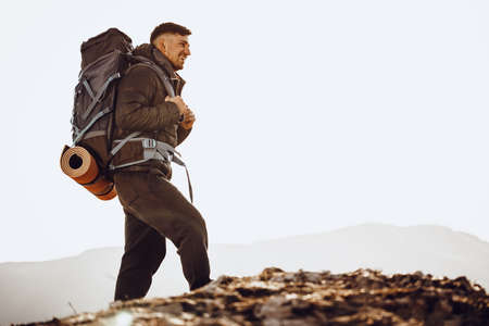 Male backpacker in hiking equipment standing at the top of the mountainの写真素材