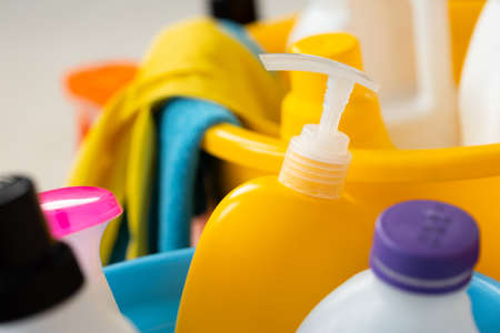 Various household cleaning detergents and bottles in a plastic bucket on the floorの写真素材