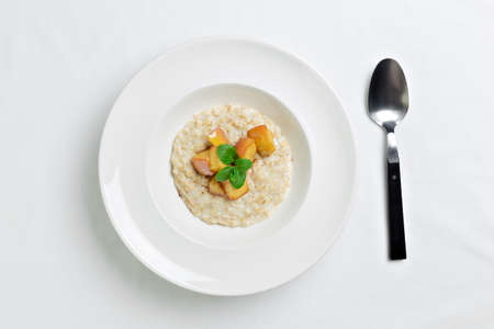 Oatmeal porridge with baked apple in white bowl