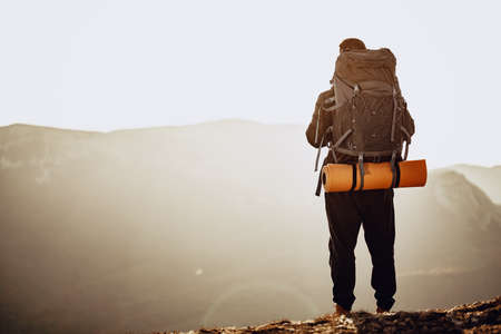 Man hiker got to the top of the mountain and looks down onto the valley