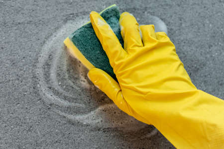 Womans hands in yellow gloves cleaning counter top in kitchen