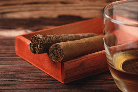 Red wooden box with rolled cigars on wooden table close upの写真素材