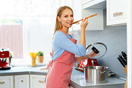 Attractive young blonde woman checking cooked food