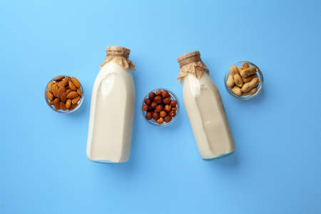 Bottles of vegan non dairy milk with various nuts on blue backgroundの写真素材