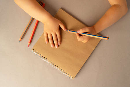 Kids hands writing in open notebook, top view, copy space