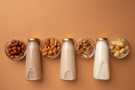 Bottles of nut non dairy milk on brown background flatlayの写真素材
