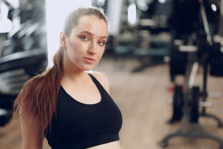 Brunette young woman sitting tired in a gym after workoutの写真素材