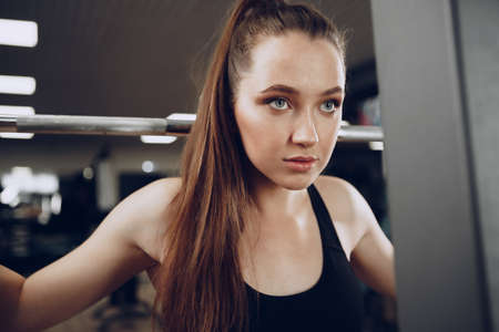 Attractive young woman doing exercises for the muscles of the arms and back in a gymの写真素材