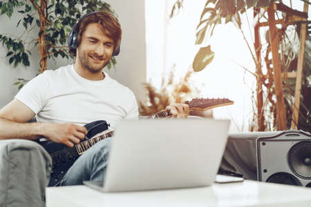 Man playing electric guitar and recording music into laptopの写真素材