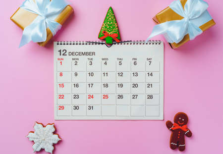 Calendar page of december with festive decorations on pink background