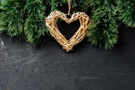 Fir tree branches with wooden heart on black