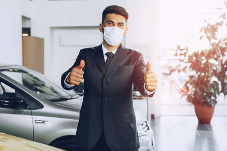Man car dealer wearing protective medical mask on his working placeの写真素材