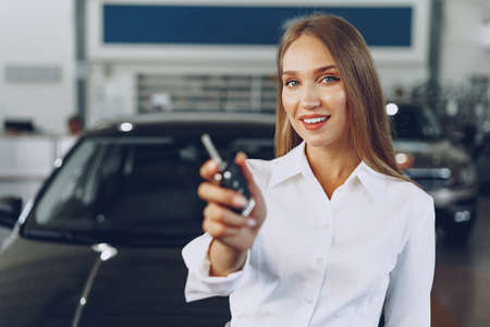 Young happy woman buyer/seller near the car with keys in hand