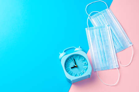 Blue alarm clock and medical face mask