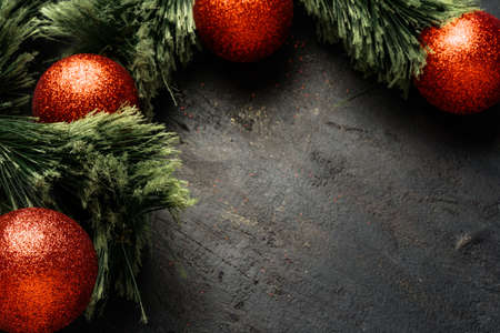 Christmas background with fir tree branches and red baubles on black