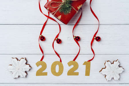 Packed small Christmas gifts and red baubles on white wooden boardの写真素材