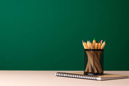 School supplies on wooden desk against green chalkboardの写真素材