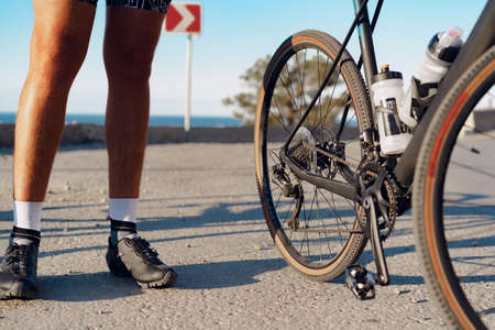 Cyclist man feet and bike wheel on coastal roadの写真素材