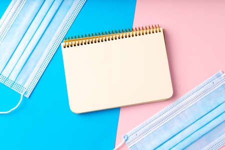 Medical face mask on pink and blue paper background with copy spaceの写真素材