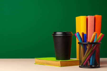 School supplies on wooden desk against green chalkboardの写真素材