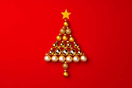 Christmas tree made of gold baubles on red backgroundの写真素材