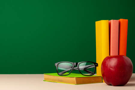 Pile of books and red apple on desk
