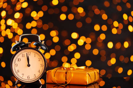 New Year eve concept with alarm clock against blurred garlandの写真素材
