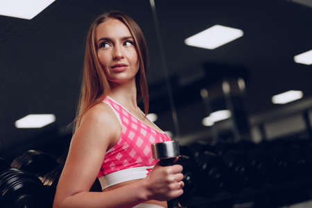 Portrait of a young woman in sportswear posing in a gymの写真素材