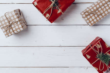 Wrapped Christmas gifts on white wooden board, top view