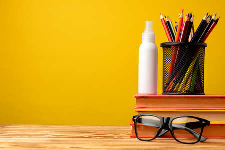 Back to school concept with stationery in cup and hand antiseptic spray