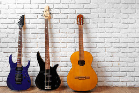 Set of guitars on the floor against white brick wall