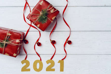 Packed small Christmas gifts and red baubles on white wooden boardの写真素材