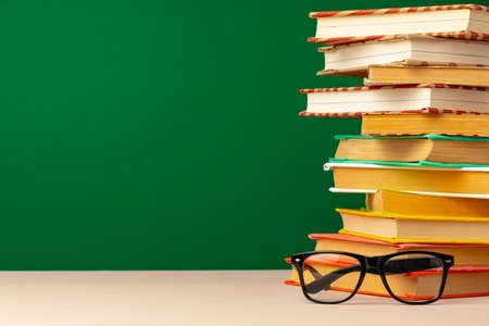 School supplies on wooden desk against green chalkboard
