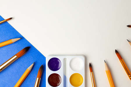 Watercolor paint box and set of brushes on blue and white background