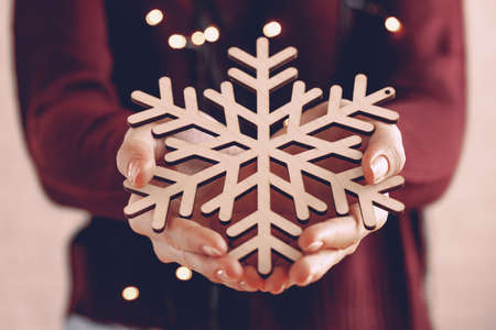 Female hands holding wooden snowflake, christmas decorationの写真素材