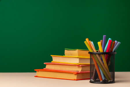 School supplies on wooden desk against green chalkboardの写真素材