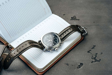 Male watch and notepad on dark grey tableの写真素材