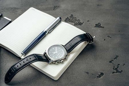 Male watch and notepad on dark grey tableの写真素材