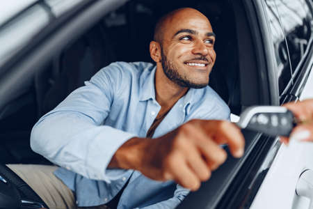 Portrait of a handsome happy African American man sitting in his newly bought car