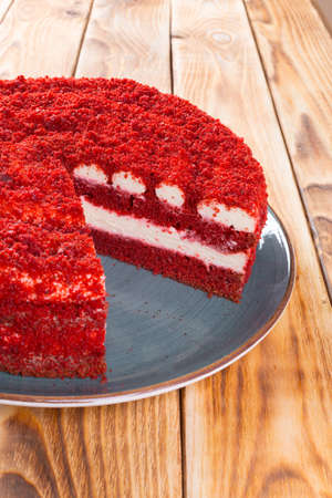 Cut red velvet cake on plate on wooden table
