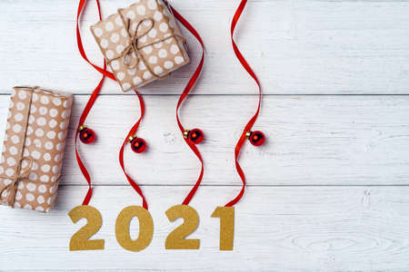 Packed small Christmas gifts and red baubles on white wooden board