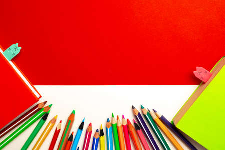Colorful pencils and notepads on paper background top viewの写真素材