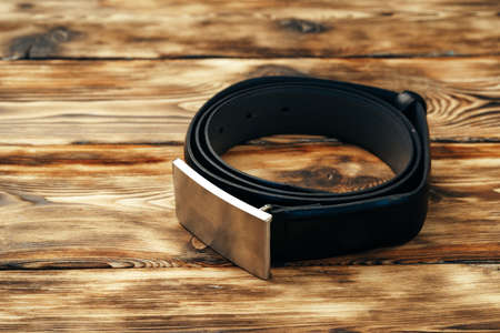Fashionable male belt on brown wooden background