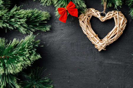 Fir tree branches with wooden heart on black