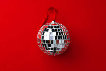 Christmas disco ball on red ribbon on red background