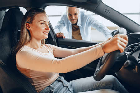 Joyful young couple looking around inside a new car they are going to buy in a car shop