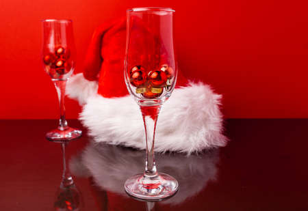 Two champagne glasses with small Christmas balls inside against red backgroundの写真素材