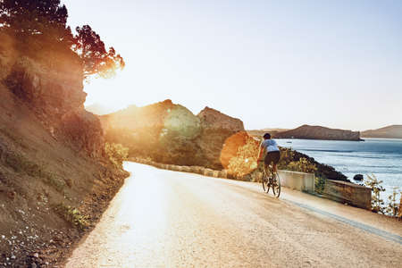 Cyclist riding on his bicycle at coastal roadの写真素材