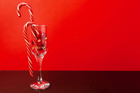 Two champagne glasses with small Christmas balls inside against red backgroundの写真素材