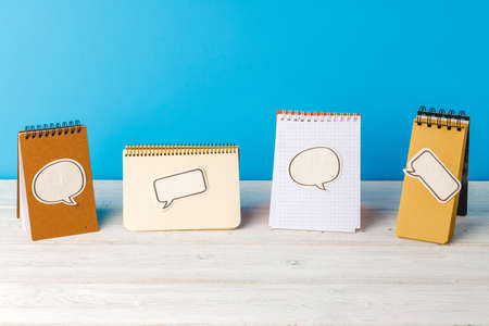 Four open spiral notepads with speech bubble stickersの写真素材